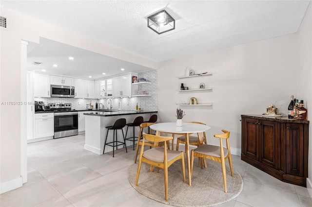 dining space featuring light tile patterned floors, baseboards, visible vents, and a textured ceiling