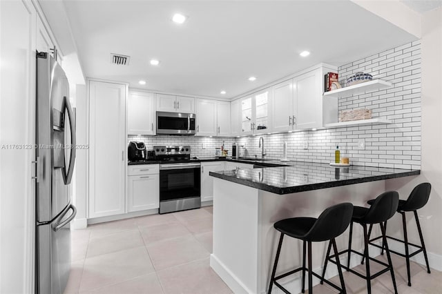 kitchen with visible vents, appliances with stainless steel finishes, a peninsula, white cabinets, and light tile patterned floors