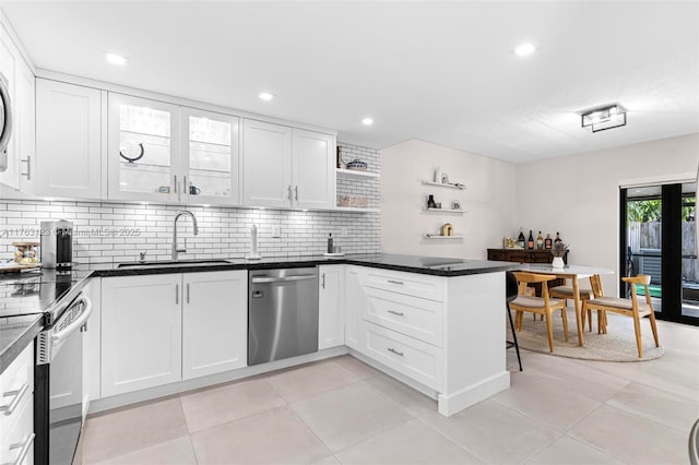 kitchen with a peninsula, open shelves, a sink, stainless steel appliances, and white cabinetry