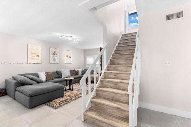 staircase with tile patterned floors, a healthy amount of sunlight, visible vents, and baseboards