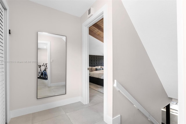 hallway featuring light tile patterned floors, visible vents, an upstairs landing, and baseboards