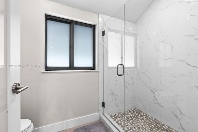 bathroom with a marble finish shower, toilet, and baseboards