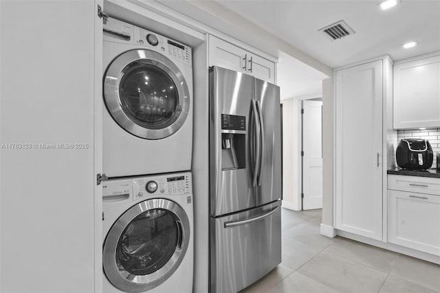 washroom featuring laundry area, light tile patterned floors, visible vents, and stacked washer / drying machine