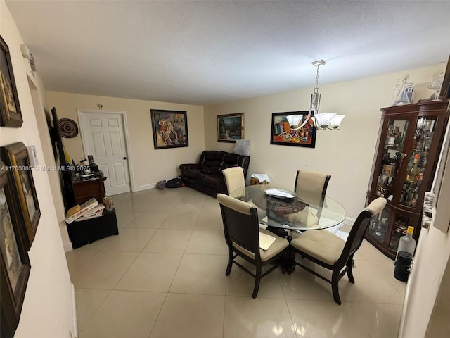 dining space with a notable chandelier, light tile patterned flooring, and baseboards