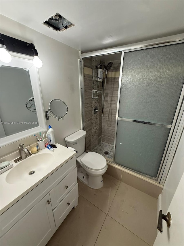 bathroom featuring tile patterned flooring, a shower stall, toilet, and vanity