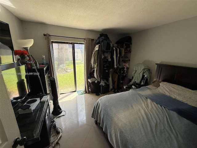 bedroom featuring access to exterior, a textured ceiling, and light tile patterned flooring