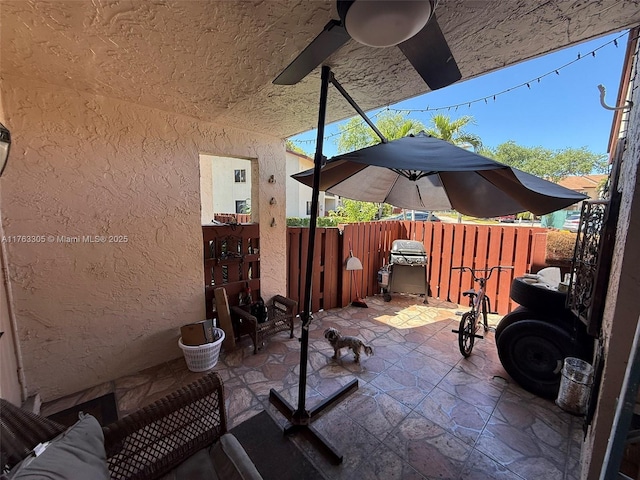 view of patio featuring a grill, ceiling fan, and fence