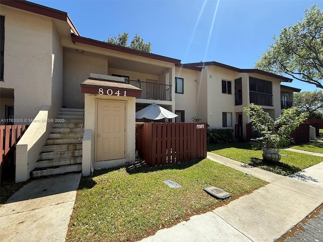 exterior space with stucco siding, a front yard, and fence