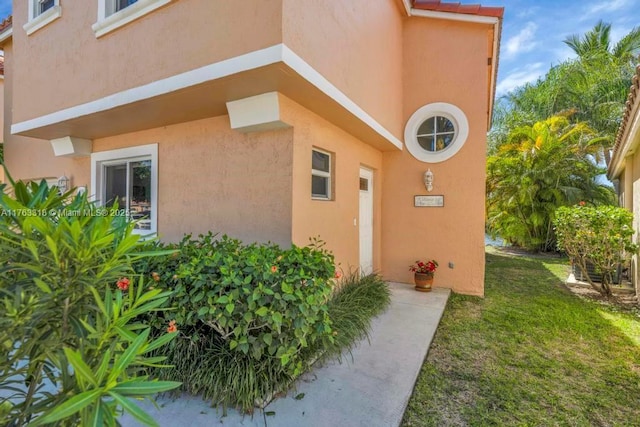 entrance to property featuring a yard and stucco siding