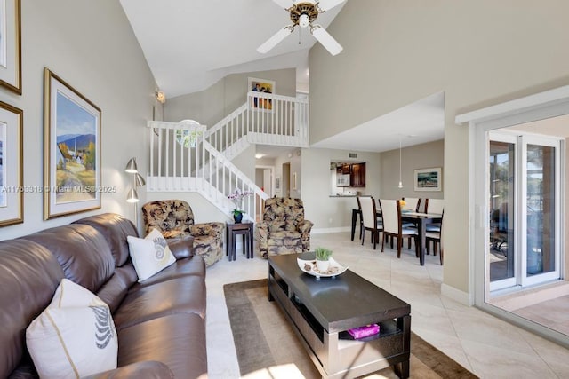 living room featuring stairway, light tile patterned floors, baseboards, high vaulted ceiling, and ceiling fan