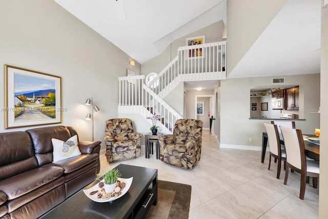 living area featuring stairway, visible vents, high vaulted ceiling, and baseboards