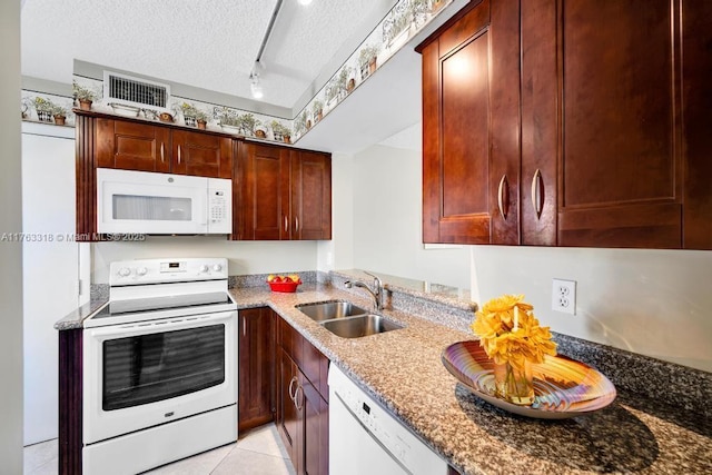 kitchen with visible vents, stone counters, white appliances, a textured ceiling, and a sink