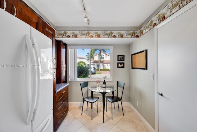 dining area featuring light tile patterned floors, track lighting, and baseboards