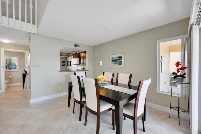 dining space featuring light tile patterned floors, visible vents, and baseboards