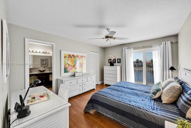 bedroom with ceiling fan, connected bathroom, a textured ceiling, and wood finished floors