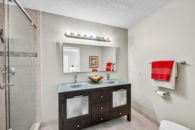 full bath featuring toilet, a stall shower, a textured ceiling, and a sink