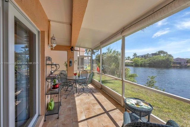 sunroom with a ceiling fan and a water view