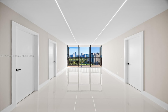 unfurnished room featuring expansive windows, a view of city, baseboards, and tile patterned flooring