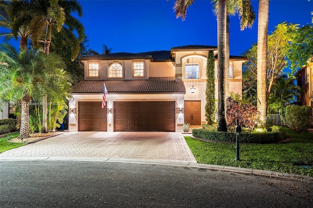 mediterranean / spanish-style home featuring stucco siding, driveway, an attached garage, and a tiled roof