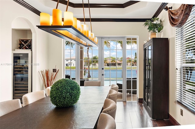 dining area with crown molding, dark wood-style flooring, beverage cooler, a tray ceiling, and french doors