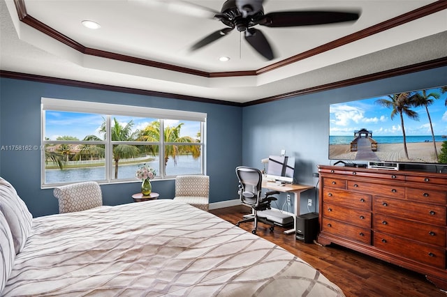 bedroom featuring a tray ceiling, crown molding, dark wood-style flooring, and baseboards