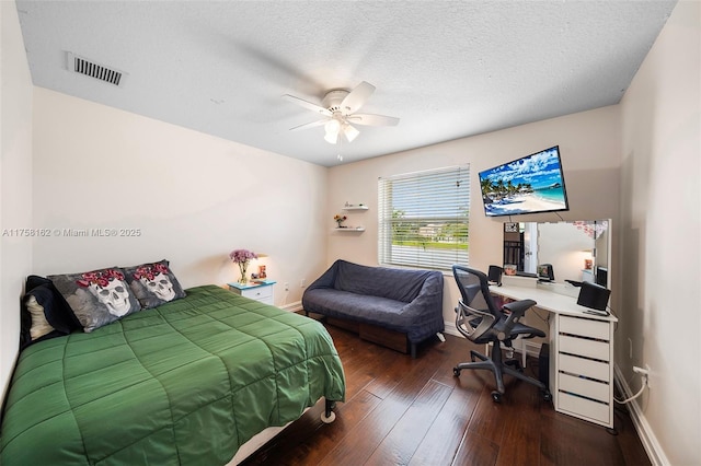 bedroom featuring visible vents, a textured ceiling, dark wood finished floors, baseboards, and ceiling fan