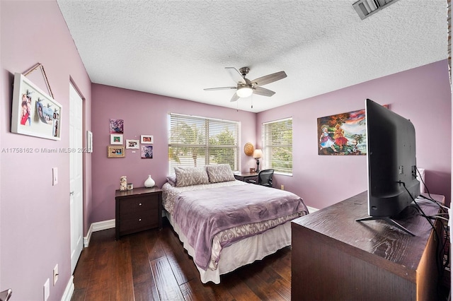 bedroom featuring visible vents, dark wood-type flooring, a textured ceiling, baseboards, and ceiling fan