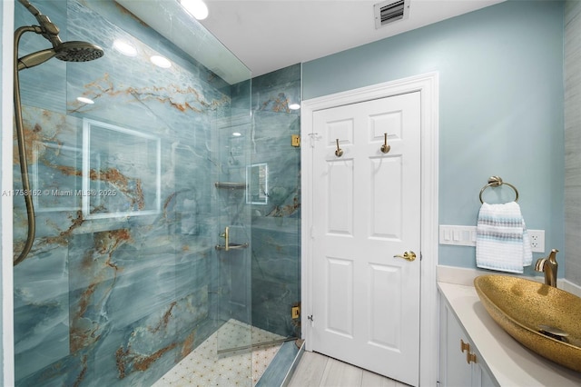 full bath featuring a marble finish shower, visible vents, and vanity