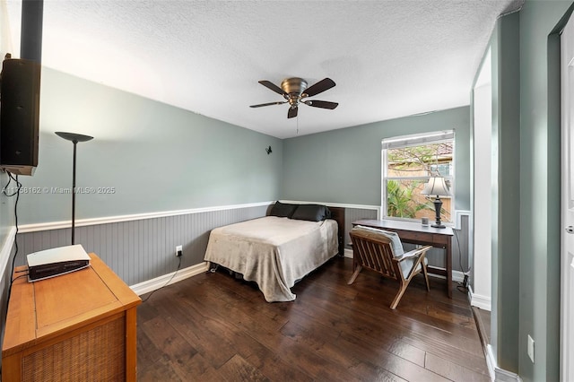 bedroom with wood-type flooring, a textured ceiling, and wainscoting