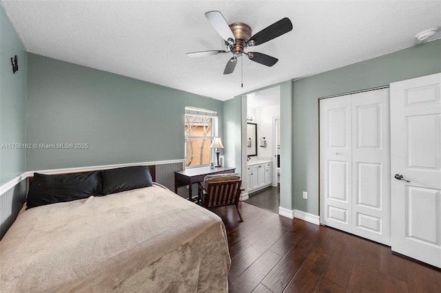 bedroom featuring ensuite bath, dark wood-style flooring, ceiling fan, a closet, and a textured ceiling