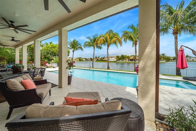 view of pool with a fenced in pool, a ceiling fan, a patio area, and a water view