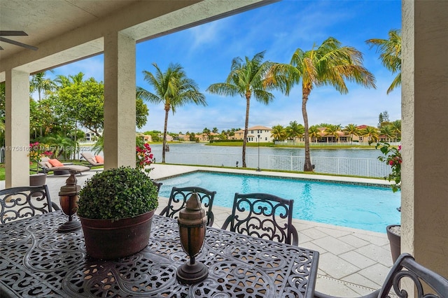 outdoor pool featuring fence, a ceiling fan, a patio, and a water view