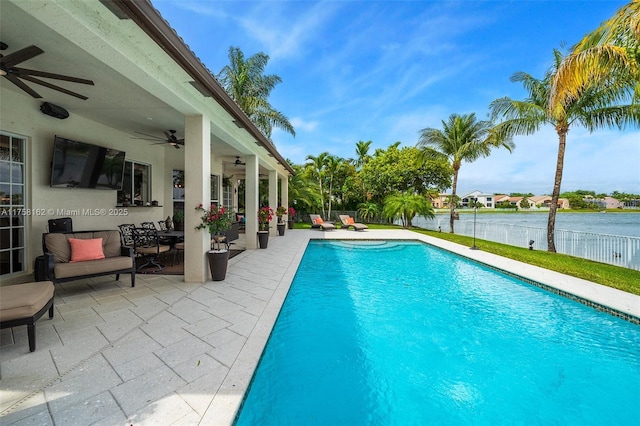 view of swimming pool with a ceiling fan, a patio area, a fenced in pool, fence, and a water view