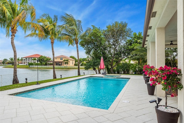 view of pool featuring a fenced in pool, a water view, a ceiling fan, and an in ground hot tub