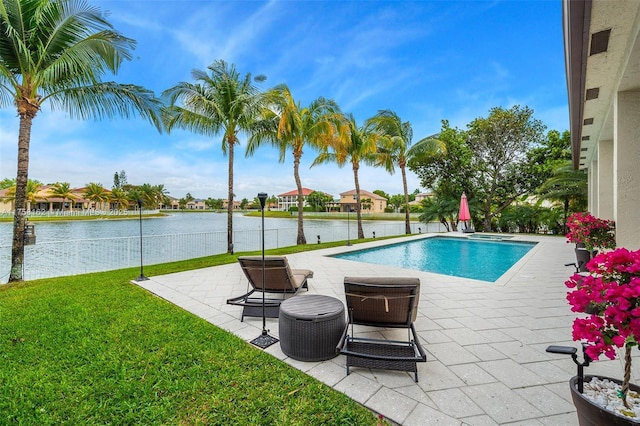 pool featuring a patio, a water view, and a yard