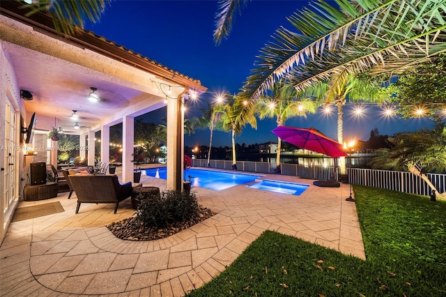 pool at night featuring ceiling fan, outdoor lounge area, a fenced in pool, a fenced backyard, and a patio