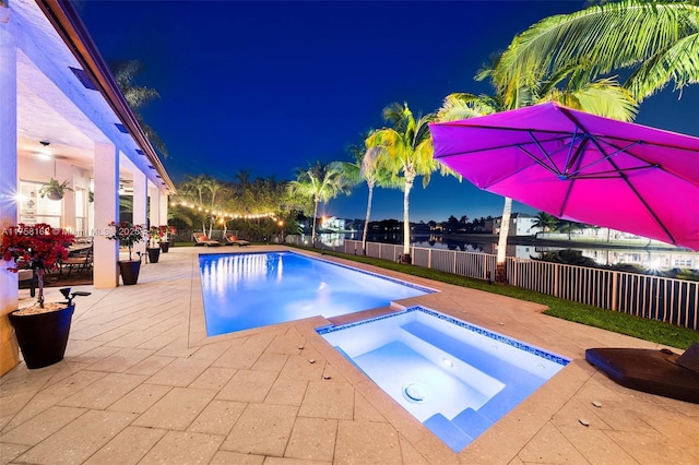 pool at twilight featuring a patio, an in ground hot tub, a fenced in pool, and fence