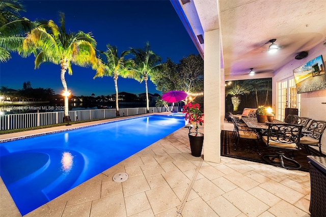 pool at twilight with a fenced in pool, french doors, a fenced backyard, a ceiling fan, and a patio