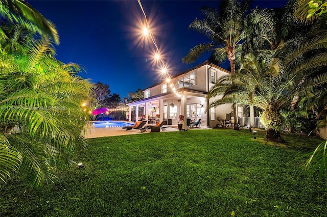 yard at twilight featuring an outdoor pool and a patio area