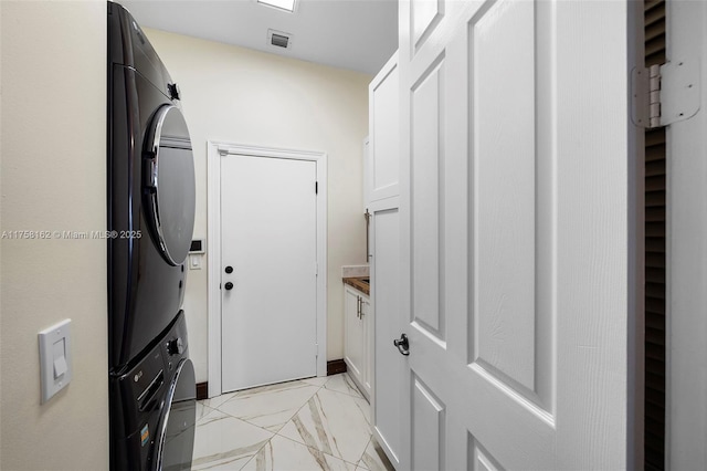 laundry area featuring visible vents, baseboards, laundry area, stacked washer / drying machine, and marble finish floor