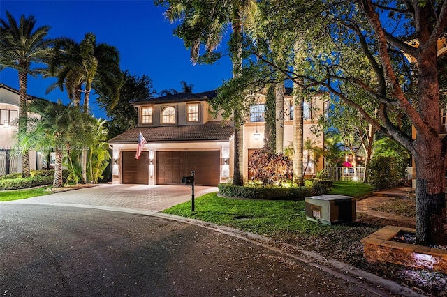 mediterranean / spanish house featuring a tile roof, stucco siding, driveway, and an attached garage