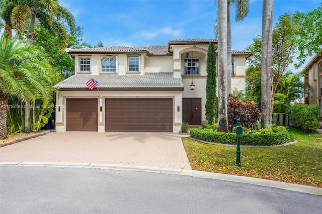 mediterranean / spanish-style house featuring stucco siding, a tile roof, and decorative driveway