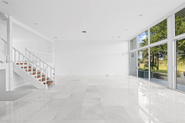 unfurnished room with stairway, floor to ceiling windows, and visible vents