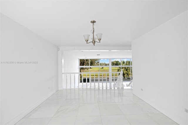 empty room featuring a notable chandelier and baseboards