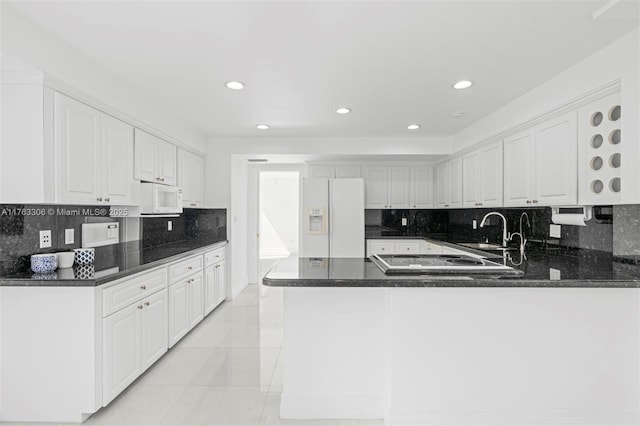 kitchen featuring white appliances, a peninsula, a sink, decorative backsplash, and white cabinetry