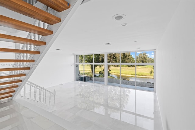 stairway featuring floor to ceiling windows and a water view