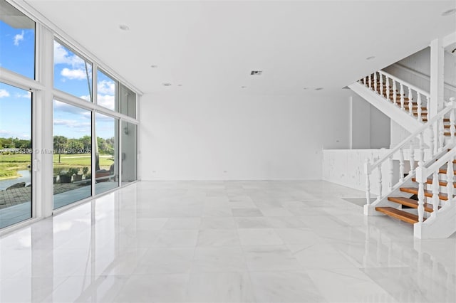 empty room featuring visible vents, recessed lighting, a wall of windows, and stairs