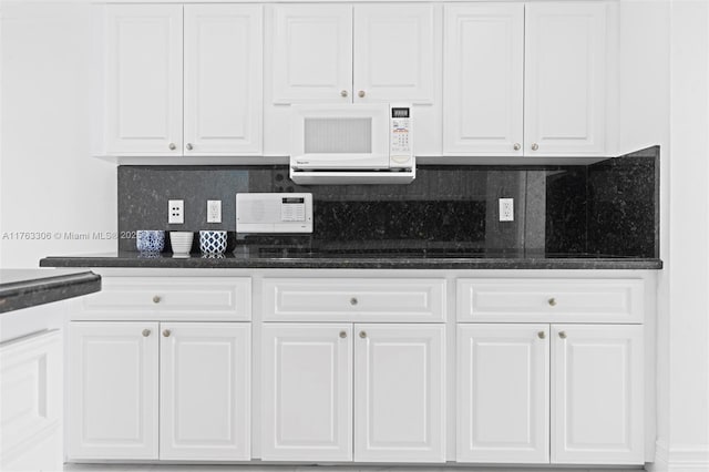 kitchen featuring white cabinetry, decorative backsplash, and white microwave