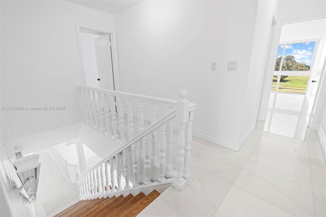 hallway with baseboards and an upstairs landing