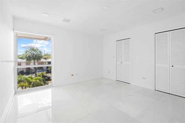 unfurnished bedroom featuring baseboards and multiple closets